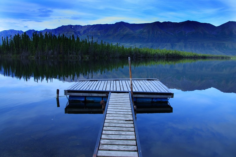 See mit Bootssteg vor einer Bergkulisse in Kanada. Foto: Manfred Baumann.